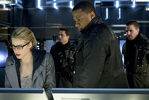 Arrow -- "My Name is Oliver Queen" -- Image AR323B_0009b -- Pictured (L-R): Emily Bett Rickards as Felicity Smoak, John Barrowman as Malcolm Merlyn, David Ramsey as John Diggle and Stephen Amell as Oliver Queen -- Photo: Liane Hentscher/The CW -- Ã?Â© 2015 The CW Network, LLC. All Rights Reserved.